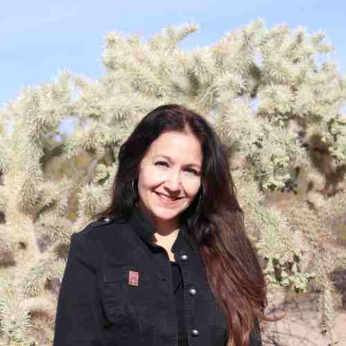 Dr. Cynthia Bejarano stands in front of a desert plant